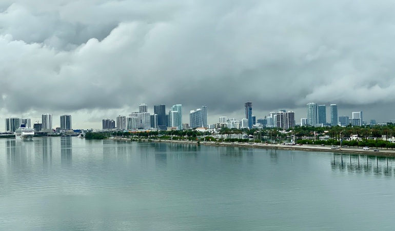 Miami city skyline across a body of water under a cloudy sky